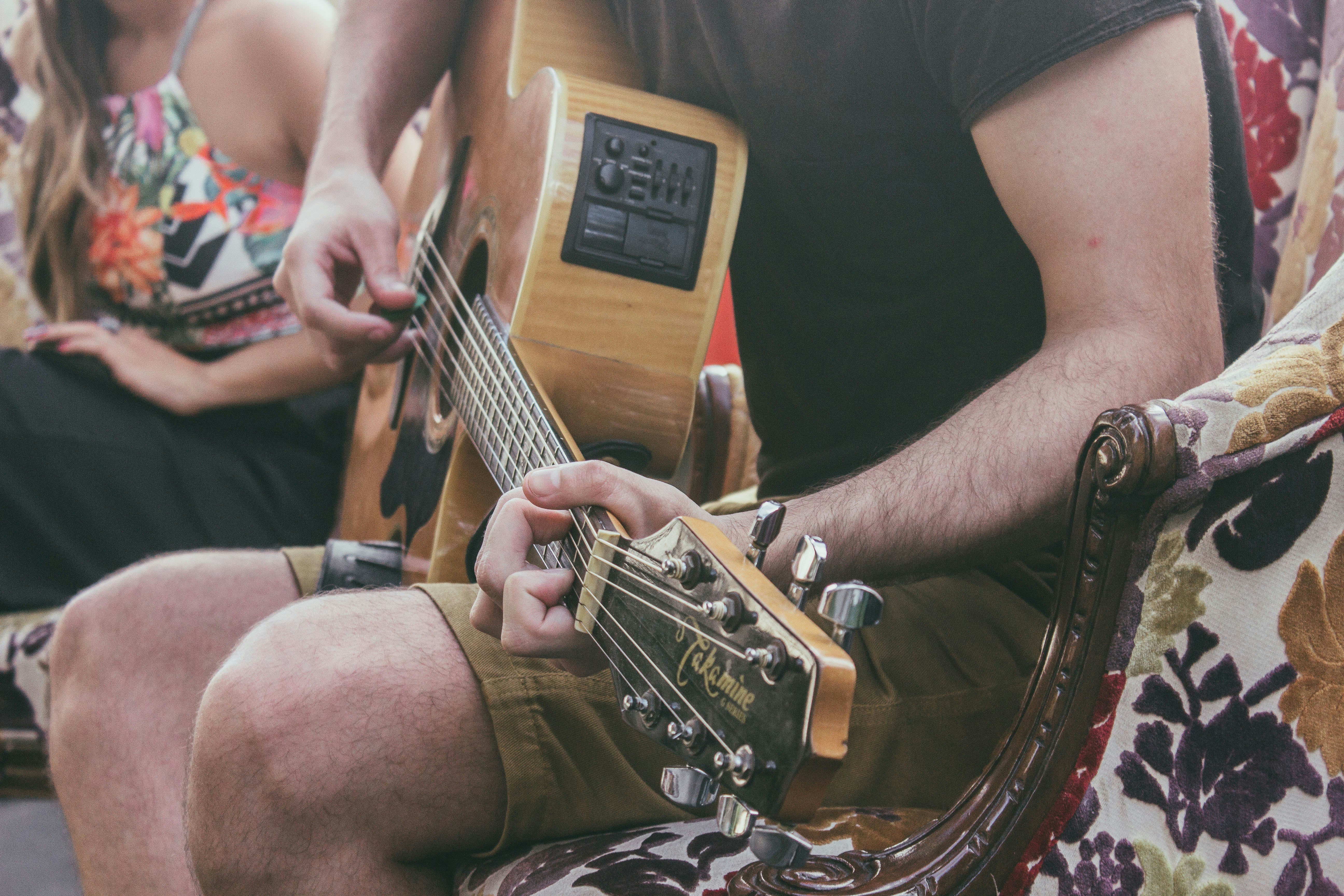 man sitting on chair while playing guitar